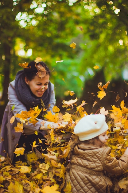 Joven madre y su hija se divierten en otoño