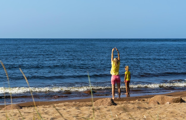 Una joven madre y su hija están caminando en una playa de arena Lago Ladoga