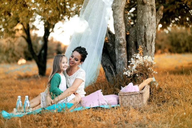 Joven madre con su hija en un picnic en el parque otoño