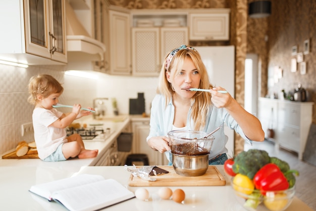 La joven madre y su hija prueban chocolate derretido.