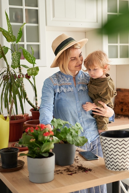 La joven madre y su hijo se dedican al cultivo de flores caseras en casa.