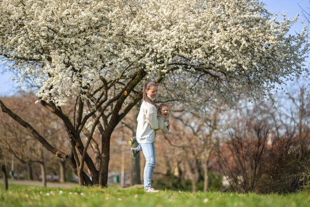 La joven madre y su linda hija se divierten en el parque de primavera en praga europa