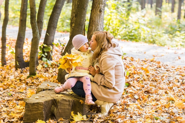 Joven madre y su niña pequeña se divierten en otoño