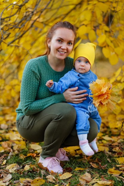 Joven madre y su niña pequeña se divierten en otoño