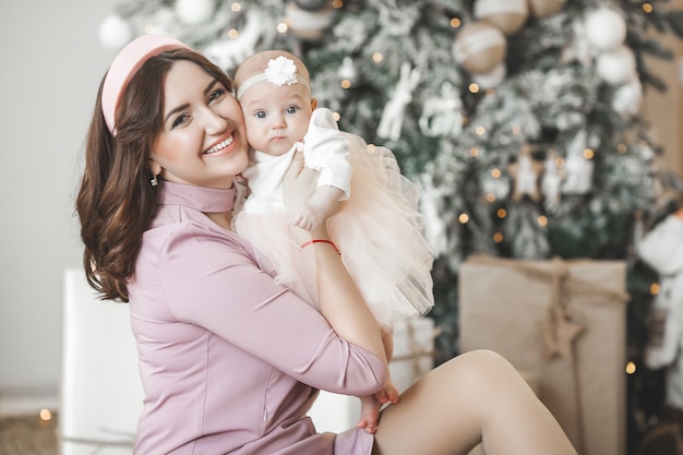 Joven madre y su pequeña hija con árbol de Navidad