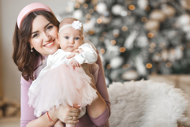 Joven madre y su pequeña hija con árbol de Navidad