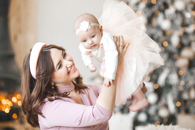 Joven madre y su pequeña hija con árbol de Navidad