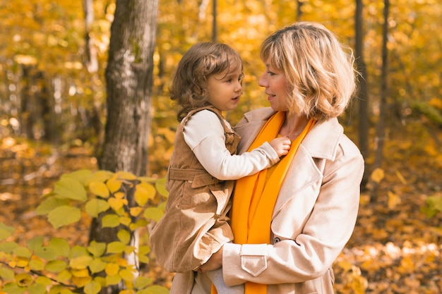 Joven madre con su pequeña hija en un parque de otoño. Temporada de otoño, concepto de crianza y niños.