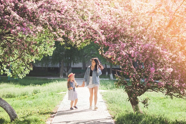 La joven madre y su pequeña y linda hija se divierten al aire libre. Chicas de familia juntas.