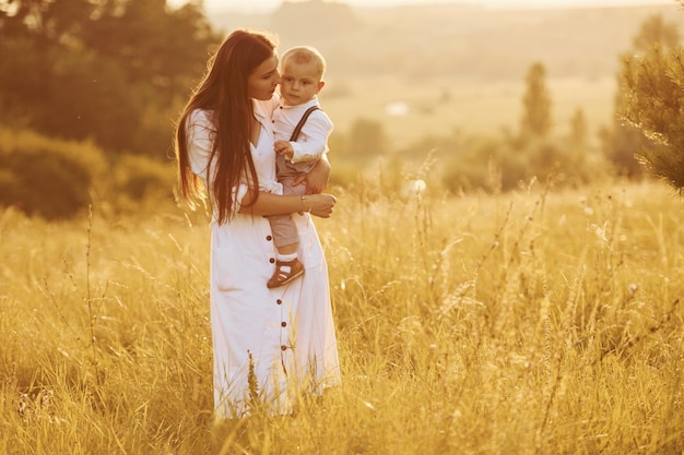 Joven madre con su pequeño hijo está al aire libre en el campo agrícola Hermoso sol