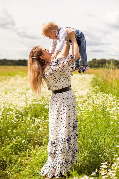 Joven madre y su pequeño y lindo hijo caminando en un campo