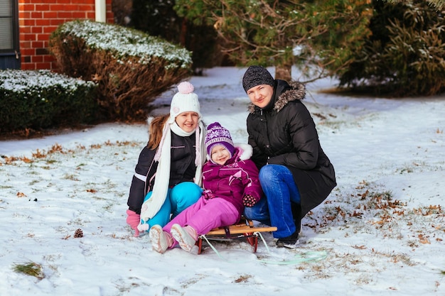 La joven madre y sus hijas se divierten el día de invierno niña jugando en la calle en invierno