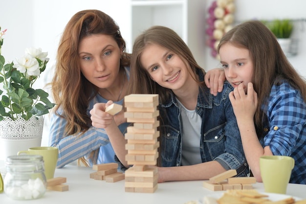 Joven madre y sus hijas jugando con bloques de madera