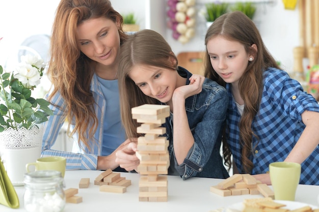 Joven madre y sus hijas jugando con bloques de madera