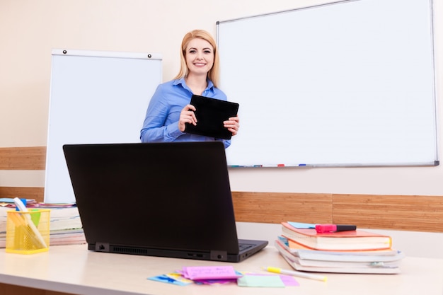 El joven maestro en el aula usa cuaderno y tecnología en las lecciones de la escuela en línea en Internet.