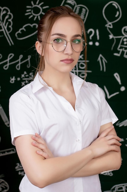 El joven maestro está de pie cerca de la pizarra en el aula