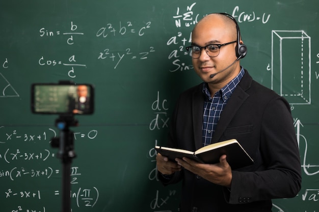 Joven maestro indio con auriculares enseñando videoconferencia en línea transmisión en vivo por teléfono inteligente