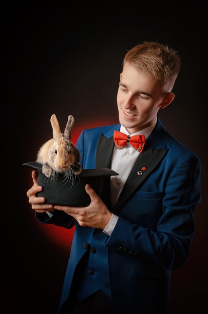 El joven mago ilusionista sosteniendo un sombrero con un conejo