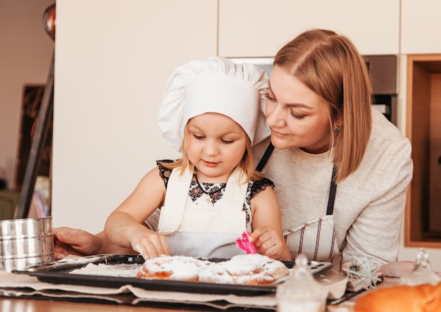 Una joven mamá engaña a una niña para que cocine bollos. Padre e hijo pasan tiempo juntos