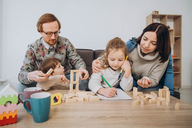 Joven mamá y papá juegan juegos educativos con niños