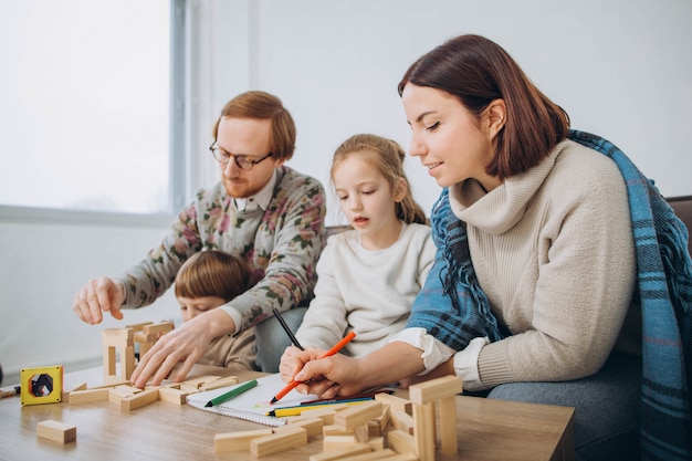 Joven mamá y papá juegan juegos educativos con niños