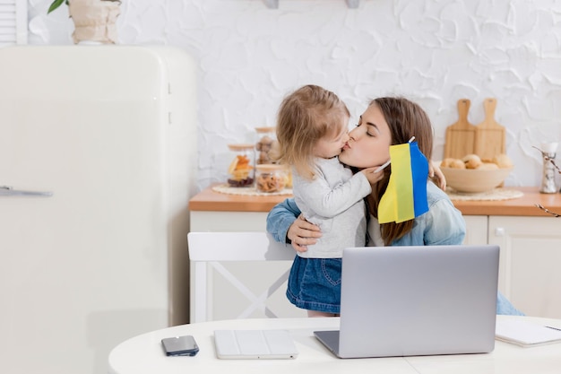 Joven mamá sonriente trabaja en casa con su lindo bebé Trabaja en casa la niña se comunica Ucrania