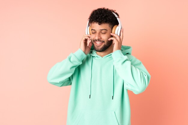 Joven marroquí aislado en rosa escuchando música y cantando