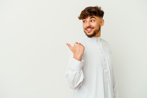 Joven marroquí con ropa típica árabe aislado en puntos blancos con el dedo pulgar, riendo y despreocupado.