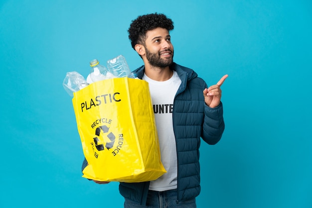 Joven marroquí sosteniendo una bolsa llena de botellas de plástico para reciclar aislado