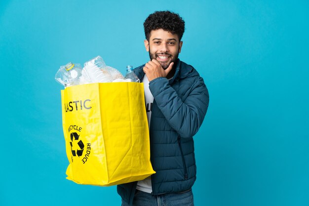 Joven marroquí sosteniendo una bolsa llena de botellas de plástico para reciclar aislado