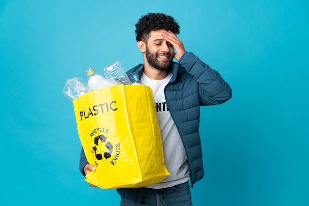Joven marroquí sosteniendo una bolsa llena de botellas de plástico para reciclar, sonriendo mucho