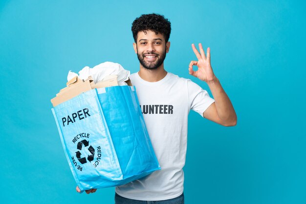 Joven marroquí sosteniendo una bolsa de reciclaje llena de papel para reciclar aislado