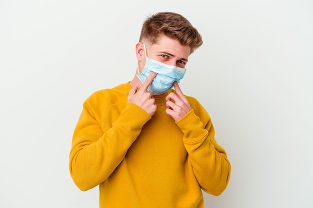 Joven con máscara para coronavirus aislado sobre fondo blanco dudando entre dos opciones.