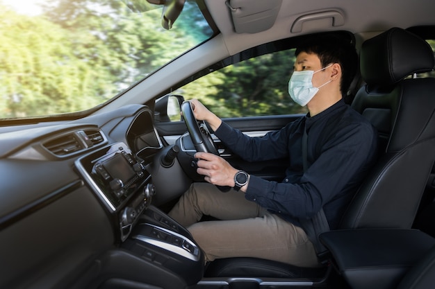 joven con máscara médica conduciendo un coche. para proteger la pandemia de covid-19 (coronavirus)