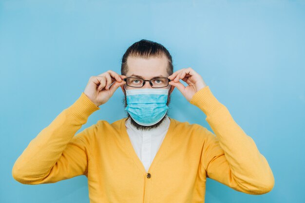 Un joven con una máscara médica. Un hombre con una chaqueta amarilla muestra un gesto con la mano. Vamos a vencer al coronavirus. La epidemia de COVID-2019. Chico positivo