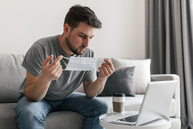 Joven con máscara médica trabajando en línea