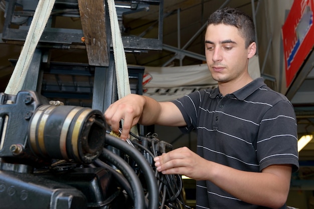 Joven mecánico reparando barcos a motor y otros