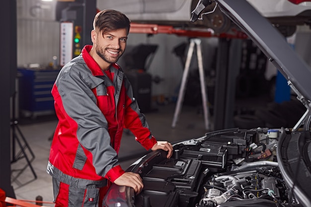 joven mecánico trabajando en el motor del coche