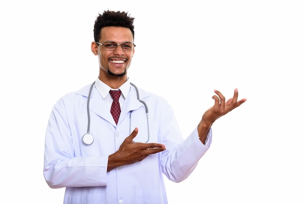 Joven médico africano feliz sonriendo mientras muestra algo aislado en blanco