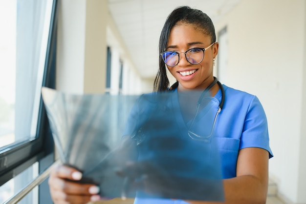 Joven médico afroamericano profesional examinando la radiografía del tórax de los pacientes