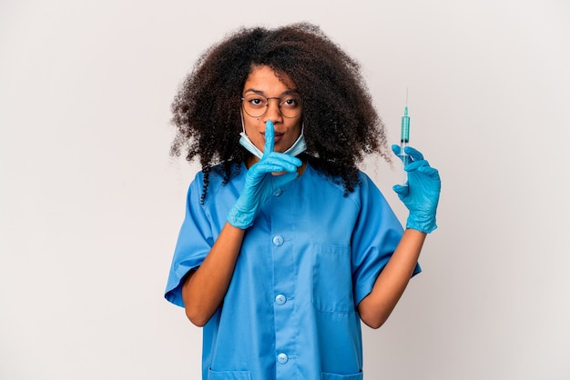 Joven médico afroamericano rizado mujer sosteniendo una jeringa manteniendo un secreto o pidiendo silencio.