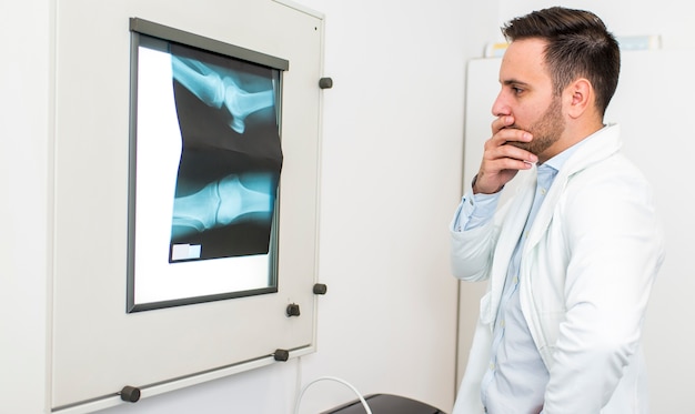 Foto joven médico analiza la imagen de rayos x en el hospital