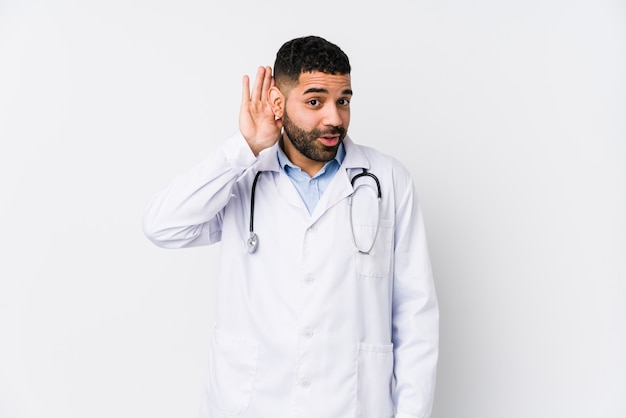 Joven médico árabe hombre tratando de escuchar un chisme.