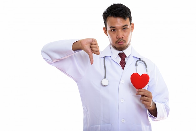 Joven médico asiático con corazón rojo y dando pulgar hacia abajo