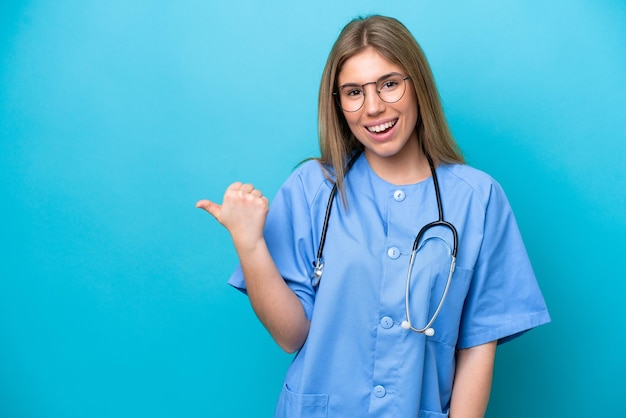 Joven médico cirujano aislado de fondo azul apuntando hacia un lado para presentar un producto