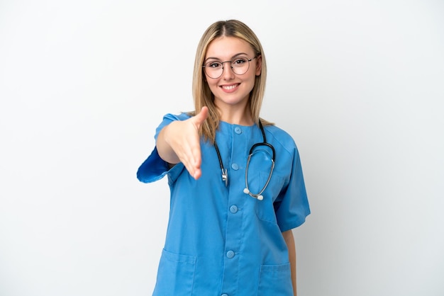 Joven médico cirujano mujer aislada de fondo blanco estrechando la mano para cerrar un buen trato