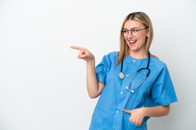 Joven médico cirujano mujer aislada de fondo blanco señalando con el dedo hacia un lado y presentando un producto