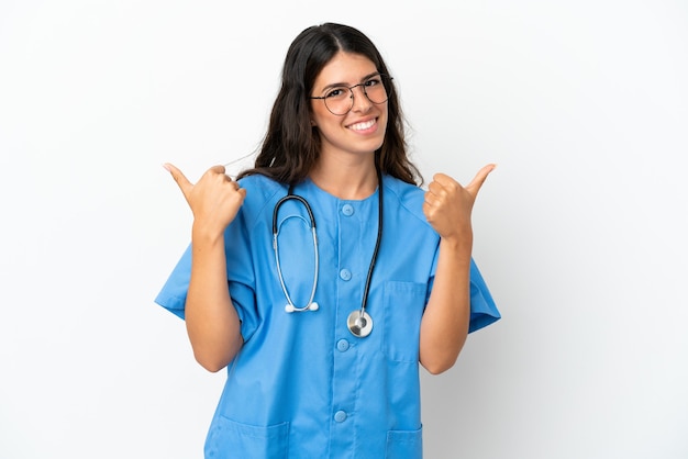 Joven médico cirujano mujer caucásica aislada sobre fondo blanco con gesto de pulgar hacia arriba y sonriente