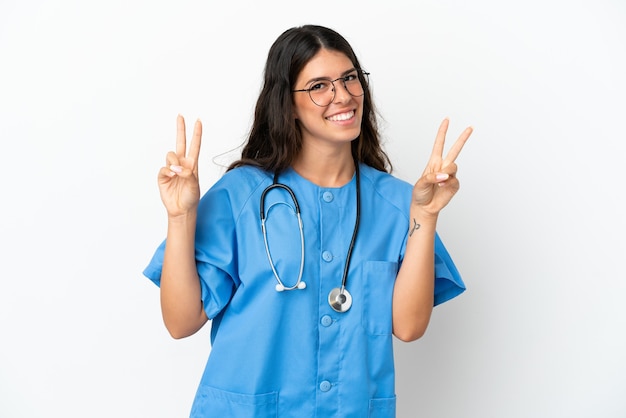 Joven médico cirujano mujer caucásica aislada sobre fondo blanco mostrando el signo de la victoria con ambas manos