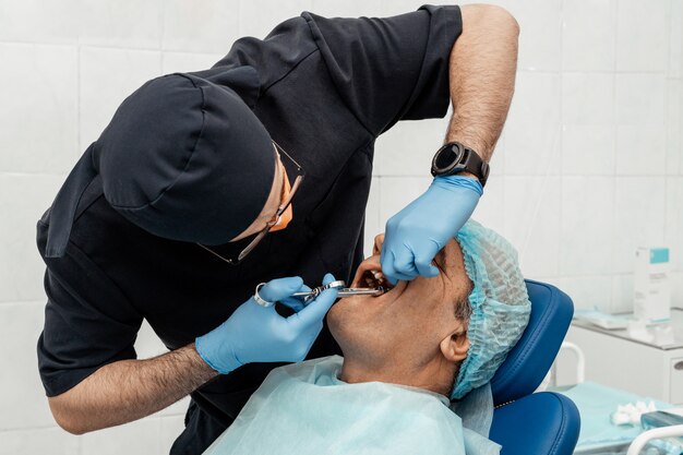 Un joven médico dentista trata a un paciente. Manipulaciones médicas en odontología, cirugía. Asistencia sanitaria Equipar el lugar de trabajo de un médico. Odontología